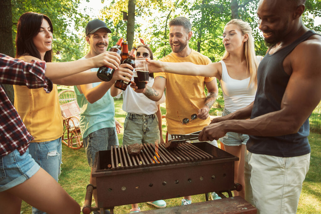 Happy friends are having beer and barbecue party at sunny day | GFD Homes Friends enjoying some drinks whilst having a bbq in the garden.