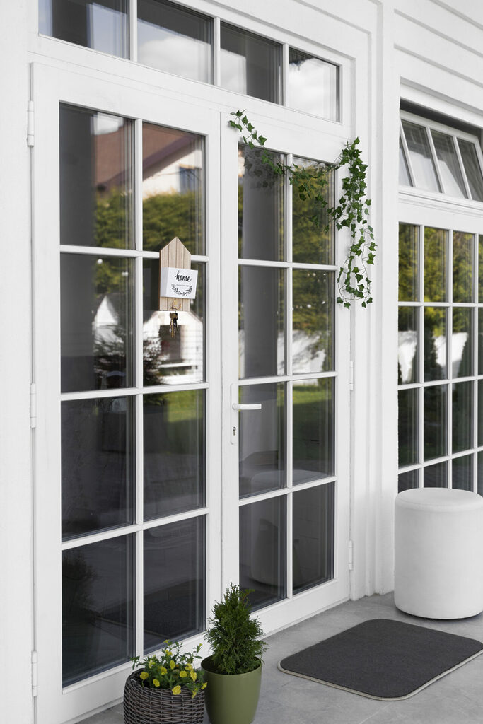 decorated-front-door-with-plant | GFD Homes Double glazed doors in white, decorated with green ivy.