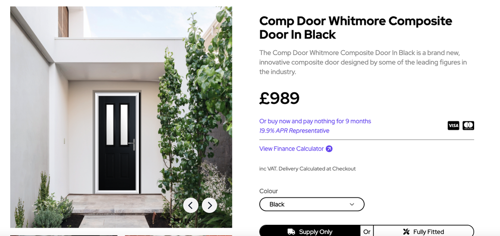 GFD Homes Black front door with a white frame set in a modern white entry, flanked by green plants and a small garden path.