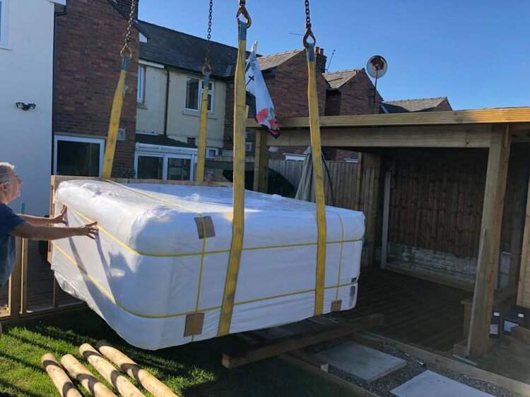 Crane lifiting a hottub into a garden