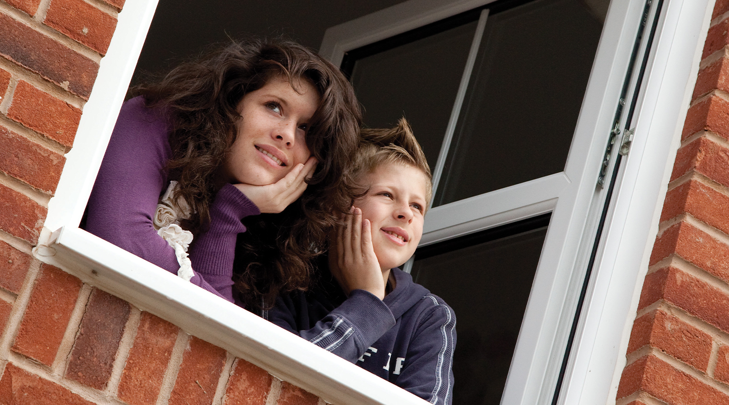 image of two children looking out of a window