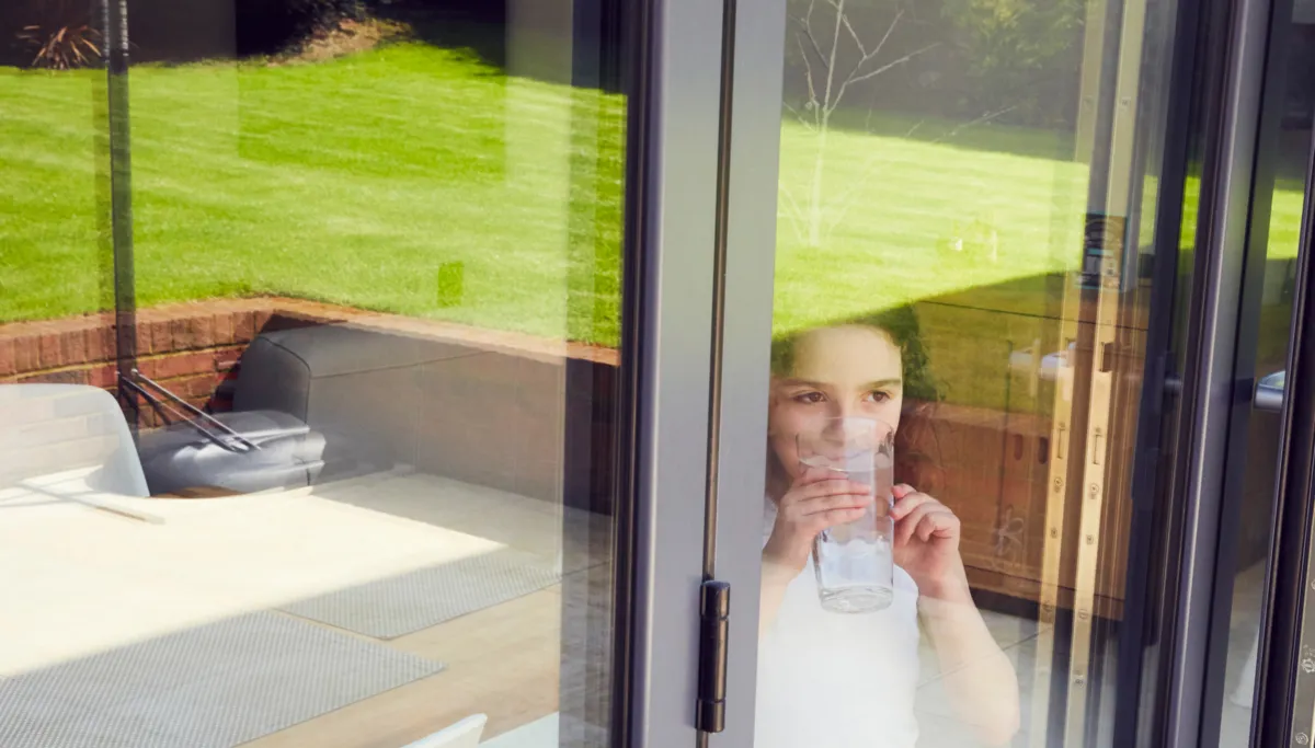 A woman and child looking out of a window with toughened safety glass